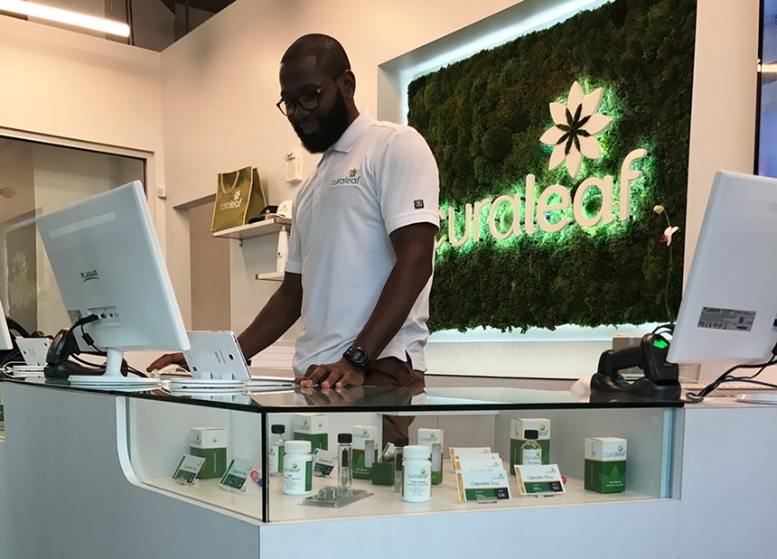 A cannabis shop attendant standing behind a computer