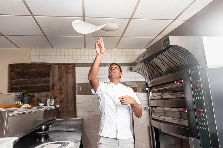 A pizza chef tossing pizza dough