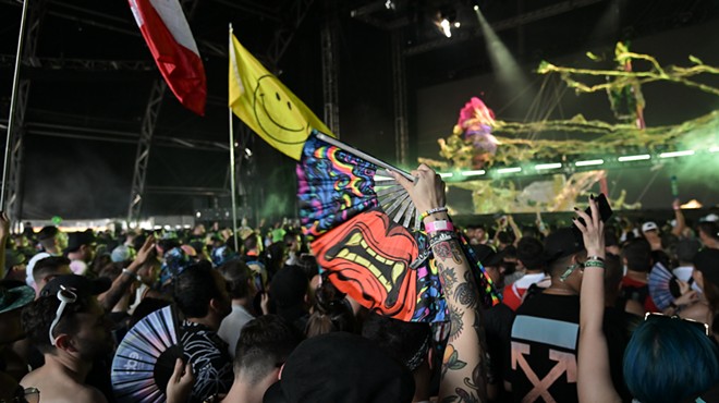 A festivalgoer holds up a colorful fan in the middle of the crowd.