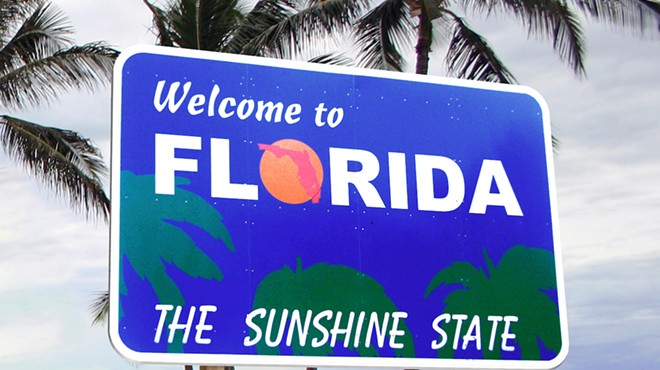 A royal blue "Welcome to Florida, The Sunshine State" sign surrounded by palm trees.